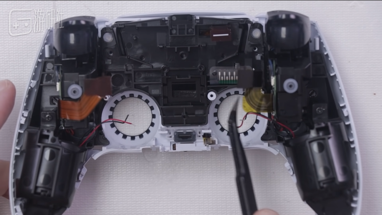 图源外媒TronicsFix提供的PS5拆解视频，左右握把处的圆筒形装置就是线性马达